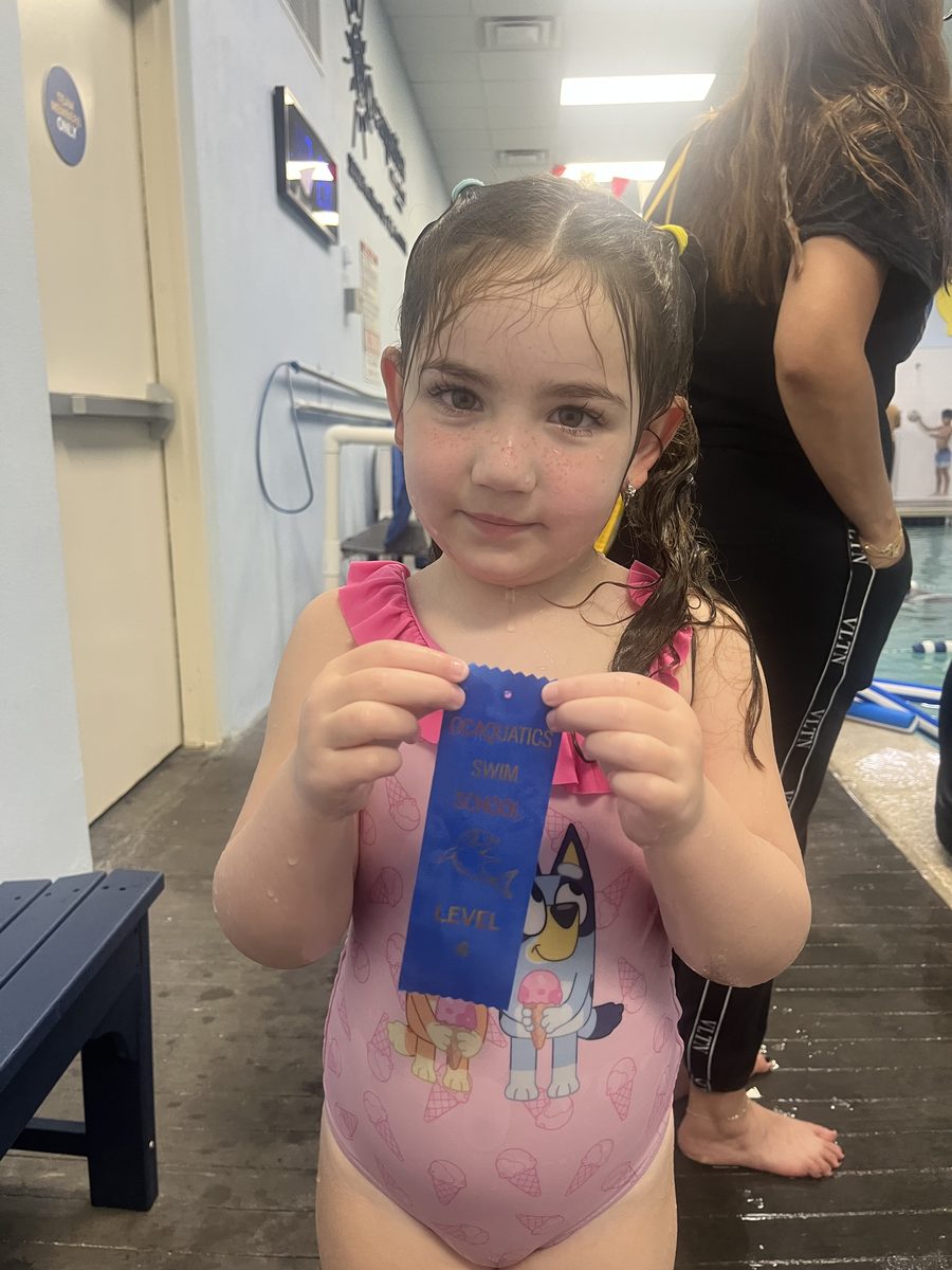 Francesca holding her latest level-up ribbon at the pool